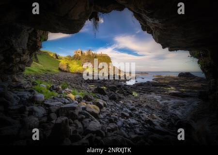 Dunluce Castle von einer kleinen Höhle an einer Küste aus gesehen, eingebettet am Rand der Klippe, Teil des Wild Atlantic Way, Bushmills, Nordirland Stockfoto