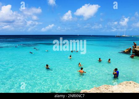 Tres Trapi Beach, Noord, Aruba - 10. März 2022. Menschen am Strand und im Wasser, Strand ist umgeben von einer vulkanischen Felsformation. Stockfoto