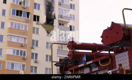 KIEW, UKRAINE - 15. NOVEMBER 2022: Ein rotes Feuerwehrauto steht vor einer abgebrannten Wohnung in einem mehrstöckigen Wohngebäude. Feuer nach dem Auspusten Stockfoto