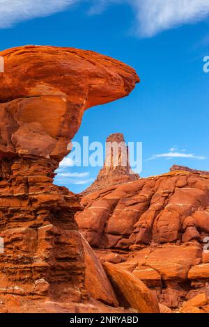 Ein Wingate Sandstone butte, eingerahmt von einer gestreiften Cutler Sandstein Felsformation am Shafer Trail bei Moab, Utah. Die weißen Streifen werden als "t" bezeichnet Stockfoto