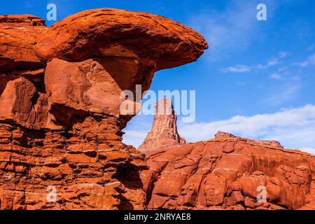 Ein Wingate Sandstone butte, eingerahmt von einer gestreiften Cutler Sandstein Felsformation am Shafer Trail bei Moab, Utah. Die weißen Streifen werden als "t" bezeichnet Stockfoto