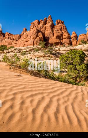 Wellen im Sand vor den Entrada Sandsteinformationen der Navajo Rocks bei Moab, Utah. Stockfoto