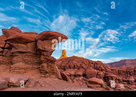 Ein Wingate Sandstone butte, eingerahmt von einer gestreiften Cutler Sandstein Felsformation am Shafer Trail bei Moab, Utah. Die weißen Streifen werden als "t" bezeichnet Stockfoto