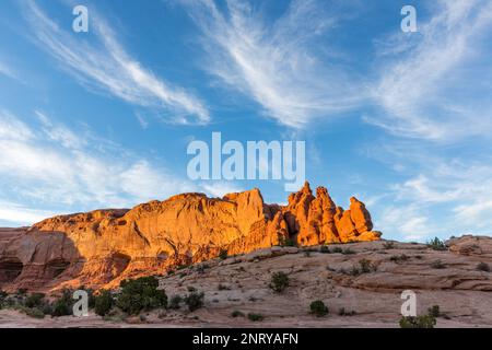 Zirrus Wolken über den Entrada Sandsteinformationen der Navajo Felsen bei Sonnenuntergang in der Nähe von Moab, Utah. Stockfoto