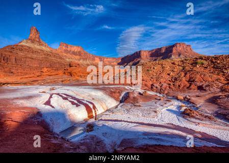 Kalium- und Salzkristalle bilden sich entlang des Randes eines Mineral Seep bei Moab, Utah, mit einem Wingate Sandstein butte dahinter. Stockfoto