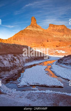 Kalium- und Salzkristalle bilden sich entlang des Randes eines Mineral Seep bei Moab, Utah, mit einem Wingate Sandstein butte dahinter. Stockfoto