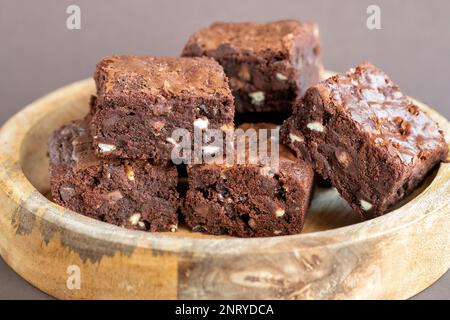 Eine Charge frisch gebackener dreifach-Schokoladen-Brownies auf einer Holzplatte. Die Brownies sind noch warm und klebrig. Ein Genuss Stockfoto