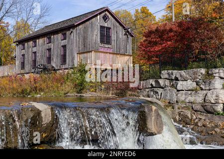 Die Grist Mill von Abraham Erb sieht malerisch hinter einem kleinen Wasserfall an der University of Waterloo in Ontario, Kanada, aus. Stockfoto