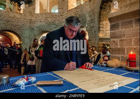 Nijmegen, Niederlande. 21. Februar 2023. Hubert Bruls, Bürgermeister von Nijmegen, sah, wie er die gefälschte Heiratsurkunde unterschrieb. Die Tradition der falschen Bauernhochzeit während des Karnevals reicht bis ins 16. Jahrhundert zurück, der Adel spielte die Rolle der Bauern und die Bauern waren die Lords. In Nijmegen waren Anja und Theo Wijlemans dieses Jahr das Hochzeitspaar des Bauern. Das Paar versammelte sich in der Valkhof-Kapelle, trug traditionelle Bauernkleidung und war umgeben von Menschen in lebhaften Kostümen. Die Hochzeit des Bauern ist eine der niederländischen Karnevalstraditionen, insbesondere in Limburg, Nord-Braba Stockfoto