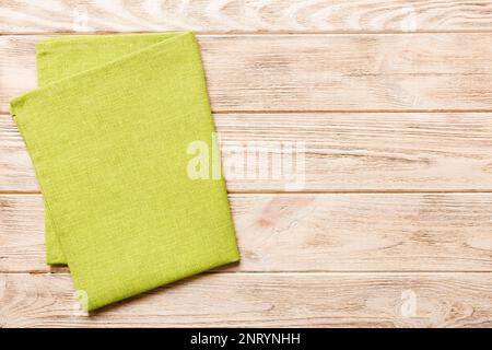 Draufsicht mit grüner Serviette auf Tischhintergrund isoliert. Gefaltetes Tuch für Modell mit Kopierbereich, flach liegend. Minimalistischer Style. Stockfoto