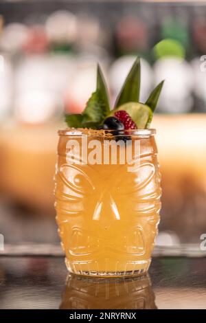 Mai-Tai-Cocktail an der Bar im Nachtklub. Tiki Rum-Getränk garniert mit Pinneapel und Blaubeeren an der Bar. Stockfoto