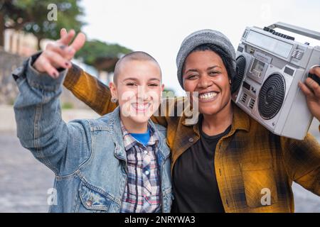 Zwei junge Frauen im urbanen Rap-Stil mit einer Boombox auf den Schultern. Konzept: Musik, Lifestyle, urbaner Stil Stockfoto