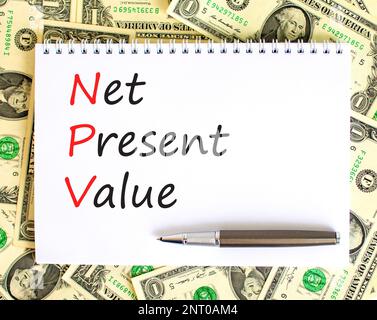 NPV net present value symbol. Concept words NPV net present value on white note on a beautiful background from dollar bills. Pen. Business and NPV net Stockfoto