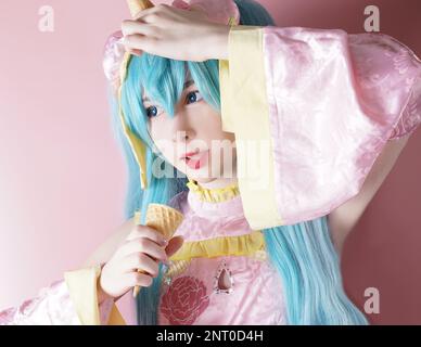 Japanisches Anime-Cosplay, Porträt von Mädchen-Cosplay mit Waffelzapfen im pinkfarbenen Raumhintergrund Stockfoto