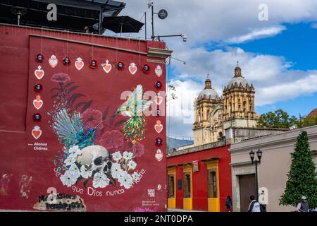 Ein Wandgemälde des Künstlers Alonxo Chavez auf einem Gebäude auf der Calle Macedonia Alcala in der historischen Stadt Oaxaca, Mexiko. Dahinter sind die Glockentürme von Th Stockfoto