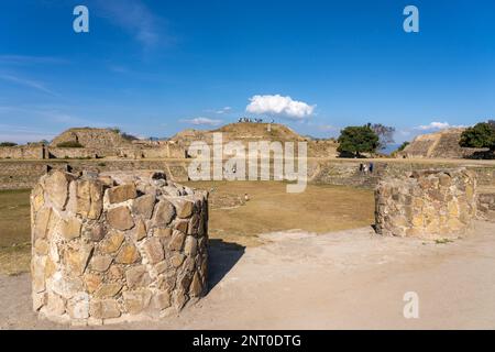 Große Steinsäulen an der gesunkenen Terrasse auf der Nordplattform in den prähispanischen Ruinen von Monte Alban, Oaxaca, Mexiko. Gebäude I (links) an Stockfoto