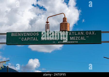 Ein Kupfermezcal, das noch auf dem Schild mit der Aufschrift „World Capital of Mezcal“ in Santiago Matatlan, Oaxaca, Mexiko steht. Stockfoto