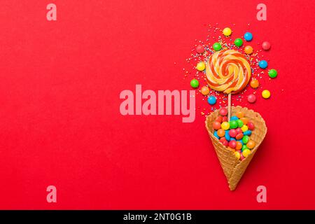 Waffelkonus voller traditioneller Süßigkeiten, die auf farbigen Hintergrund fallen, mit Platz für Kopien. Frohes Weihnachtsangebot. Stockfoto