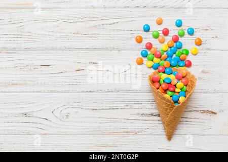 Waffelkonus voller traditioneller Süßigkeiten, die auf farbigen Hintergrund fallen, mit Platz für Kopien. Frohes Weihnachtsangebot. Stockfoto