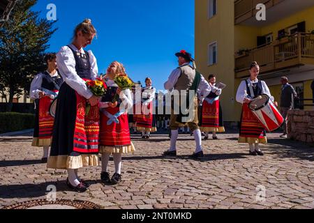 Traditionell gekleidete Leute spielen Musik während des Almabtriebs, dem Viehtrieb von der Bergweide, im Dorf Fai della Paganella. Stockfoto