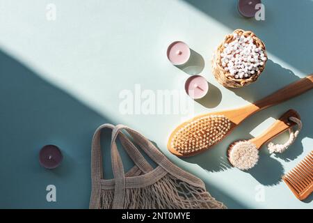 Naturkosmetik, Holzbürsten, Ohrreinigungsstäbe, Kerzen und Netzbeutel auf hellblauem Tisch mit harten Schatten. Zero Waste Konzept. Draufsicht, flach Stockfoto