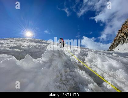 Zwei Kletterer klettern auf schneebedeckten Hängen als Seil-Team an sonnigen Tagen unter dem Mont Blanc du Tacul Mount 4248m, französische Alpen, Frankreich. Sport, Klettern, Mo Stockfoto