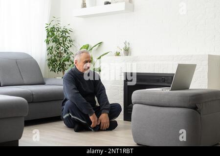 Online-Workout. Älterer Mann, der Sport macht, mit Online-Tutorial zu Hause, Panorama, freier Platz Stockfoto