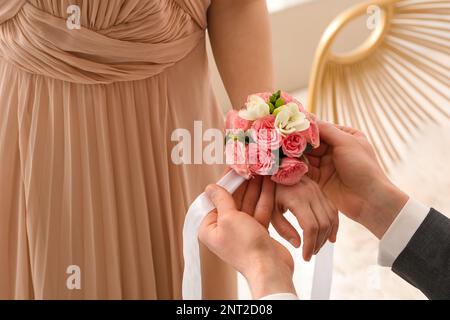 Ein junger Mann, der sein Abschlussball-Date um das Handgelenk bindet, Nahaufnahme Stockfoto