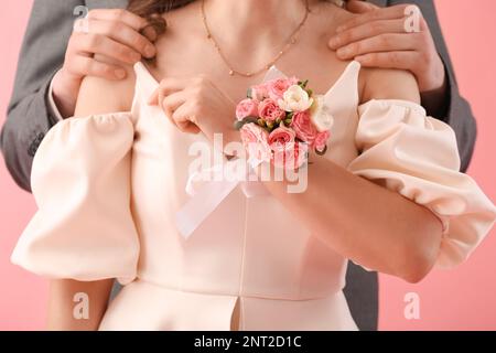 Junge Frau mit Ansteckblume und ihrem Abschlussball-Date auf pinkem Hintergrund, Nahaufnahme Stockfoto