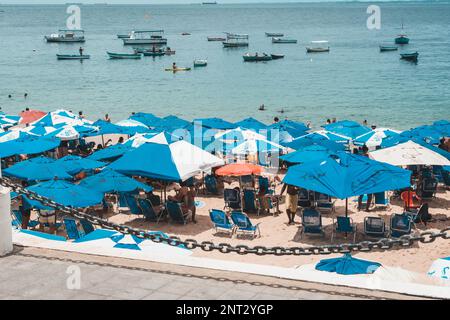 Salvador, Bahia, Brasilien - 14. Januar 2022: Mehrere Touristen schützen sich vor der starken Sonne am Strand Porto da Barra in Salvador, Bahia. Stockfoto