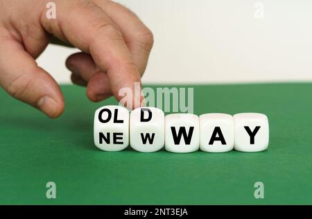 Auf einer grünen Oberfläche befinden sich weiße Würfel mit der Aufschrift „OLD WAY“ oder „NEW WAY“. Zwei Würfel werden mit einem Finger gepresst. Geschäftskonzept. Stockfoto