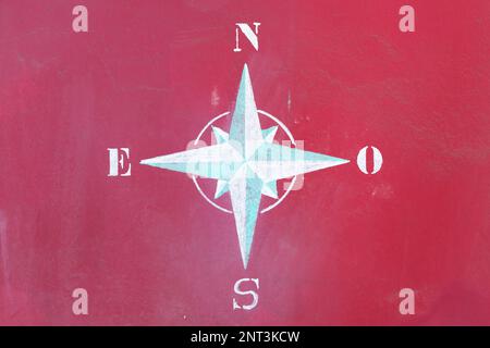 Nahaufnahme einer 8-Punkt-Kompassrose mit einer Kreide an einer roten Wand. Stockfoto
