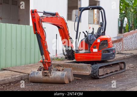 Roter Minibagger auf einer Nebenstraße. Stockfoto