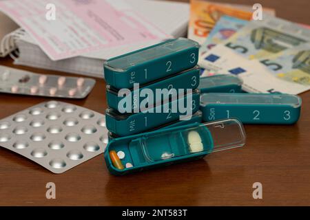 Tabletten und Pillen in einer Plastikbox für jeden Wochentag. Verschreibungspflichtige Banknoten und verschwommene Banknoten im Hintergrund. Schließen. Stockfoto