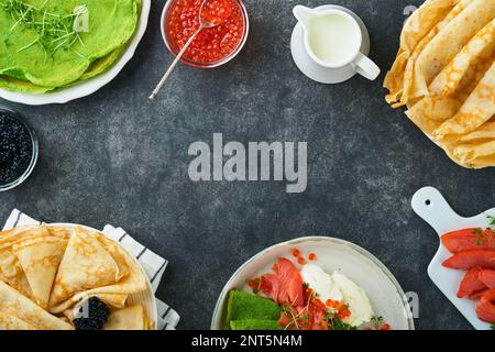 Verschiedene grüne und weiße Pfannkuchen. Dünner grüner Spinat und weiße Crepe-Pfannkuchen mit rotem und schwarzem Kaviar, Sauce auf grauem Beton-Tischbrea Stockfoto