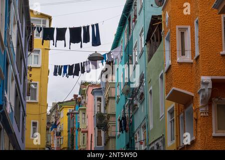 From below of clothes hanging and drying on ropes between colorful residential buildings against cloudy sky Stockfoto