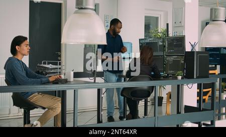 Multiethnisches Team von App-Entwicklern, das an einem Gruppenprojekt zusammenarbeitet, Algorithmus für neue Cloud-Computing-Benutzeroberfläche auf dem Computer. Vielfältiges Team von Softwareingenieuren, das Code-Ideen zusammenstellt. Stockfoto