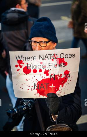 Geheimnisvoller Mann mit einem „No 2 NATO“-Schild am Stop the war march am Trafalgar Square, London (Februar 2023). Stockfoto