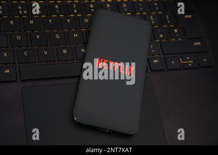 Die Netflix-App wird auf einem iPhone auf einem Laptop geladen Stockfoto
