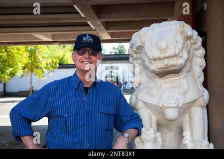 Senior-Mann posierte mit Löwenstatue an einem Schrein in Chinatown, Vancouver, British Columbia, Kanada, 2012 Stockfoto