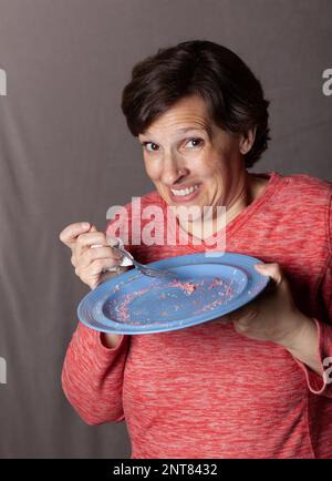 Ältere Frau mit leerem blauem Teller Stockfoto