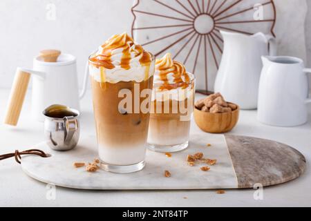 Eiskaramell-Latte in einem großen Glas mit Tropfen Karamellsauce, ausgefallenem Kaffeegetränk Stockfoto