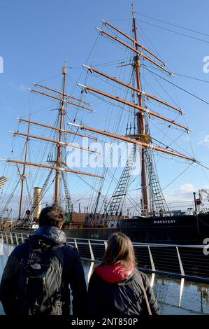 DUNDEE, SCHOTTLAND - 26. FEBRUAR 2023: Zwei Touristen sehen sich RRS Discovery an, Captain Robert Falcon Scotts Schiff, mit dem er zur Antarktis segelte Stockfoto