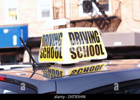 Nahaufnahme eines großen Fahrschulschildes auf dem Dach eines Übungswagens in einer belebten Straße Stockfoto