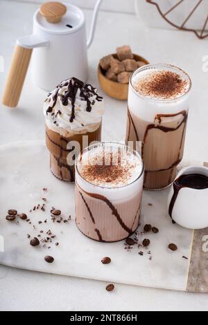 Schokoladenfrappe in verschiedenen Gläsern mit Schokoladensirup, ausgefallenen Kaffeegetränken Stockfoto