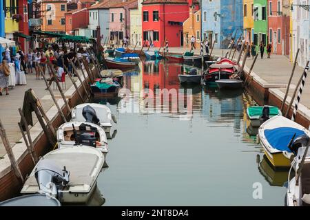Festgemachte Boote auf einem Kanal mit bunten Stuckhäusern, Geschäften und Touristen, Burano Island, Venezianische Lagune, Venedig, Veneto, Italien. Stockfoto