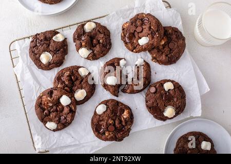 Doppelte Schokoladenkekse mit kleinen Marshmallows auf Pergament auf einem Kühlregal Stockfoto