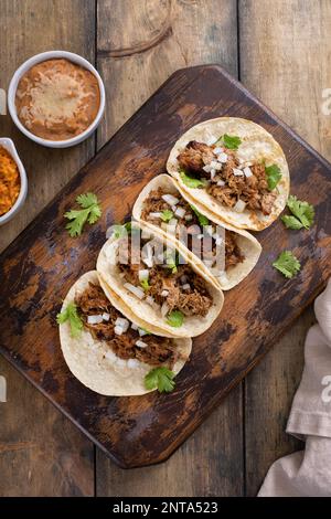 Carnitas-Tacos vom Schwein auf einem Schneidebrett mit Zwiebeln und Koriander Stockfoto