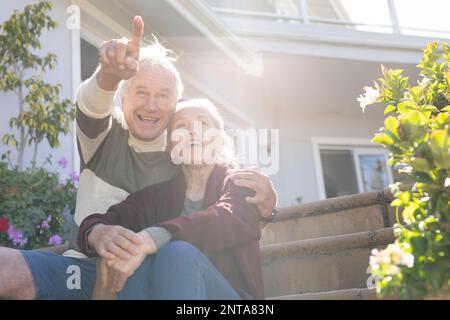 Glückliches, abwechslungsreiches Seniorenpaar, das sich im Garten umgibt und zeigt Stockfoto