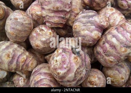 Nahaufnahme eines Stapels Jerusalem-Artischocken, die an einem Marktstand verkauft werden. Stockfoto